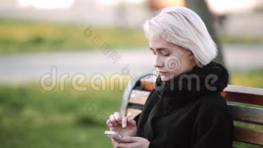 外面的金发女孩。 看着智能手机。 看着智能手机玩游戏。